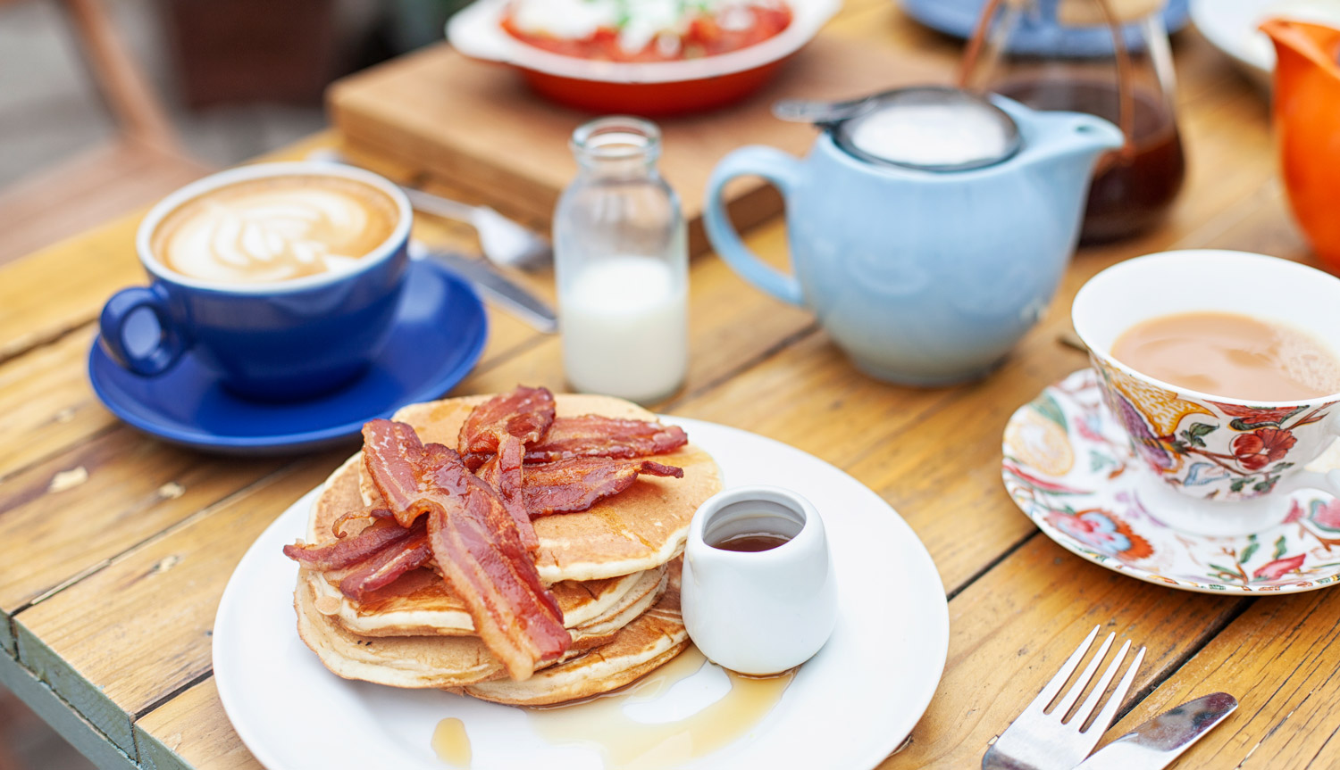 Brunch table, with bacon, pancakes and syrup, tea and coffee